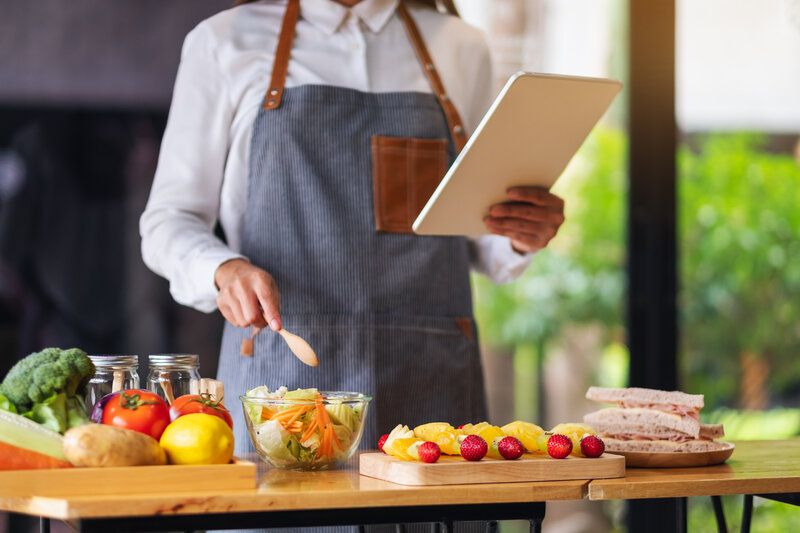 Person hält beim Kochen Tafel in der Hand